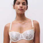 Model wearing Chantelle Fleurs Satin Half Cup Bra in ivory, delicate lace and satin overlay, low neck bridal bra.