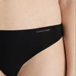 Side angle of Calvin Klein Invisibles Thong Black, highlighting the medium rise waist and logo detail on waistband.