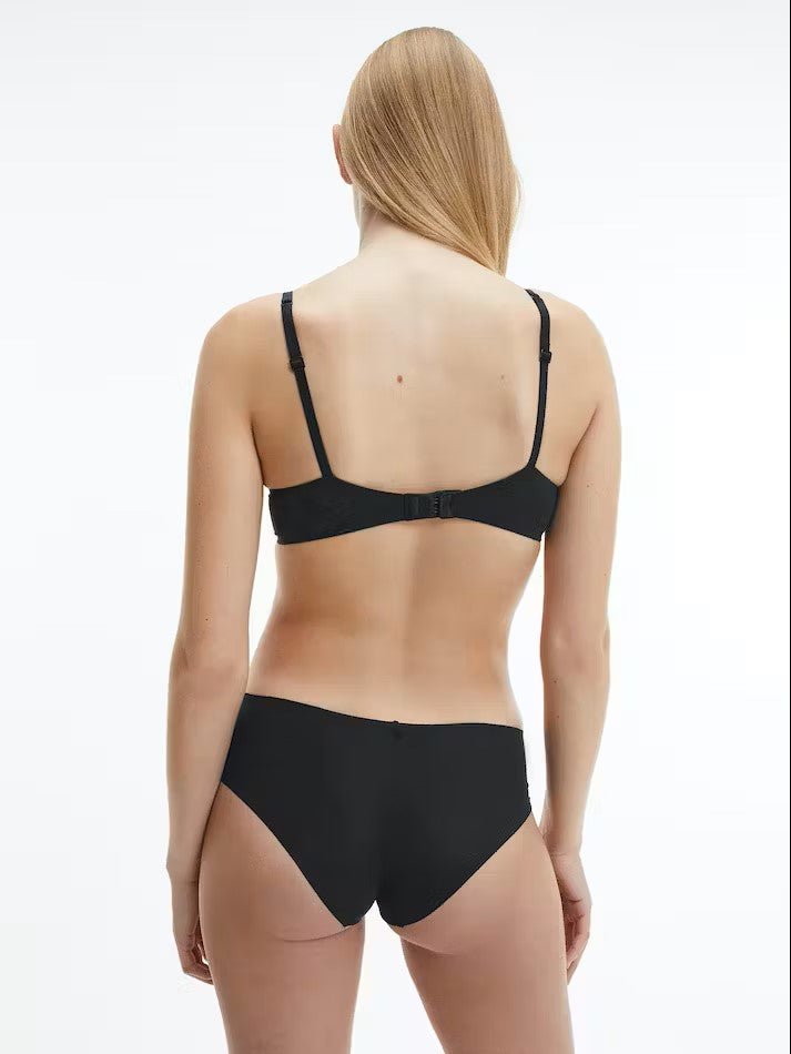 Back view of model in Calvin Klein Perfectly Fit T-Shirt Bra Black, showing adjustable straps and logo detail on the band.