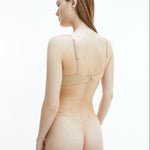 Back view of model in Calvin Klein Perfectly Fit T-Shirt Bra Bare, showing logo detail on band and adjustable nude straps.