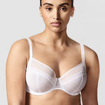 Model wearing Chantelle Parisian Allure Covering Bra in White from The Foundation, featuring semi-sheer cups, plunge neckline, and racerback straps.