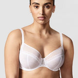 Model wearing Chantelle Parisian Allure Covering Bra in White from The Foundation, featuring semi-sheer cups, plunge neckline, and racerback straps.
