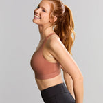 Woman wearing a sports bra and leggings on a gray background