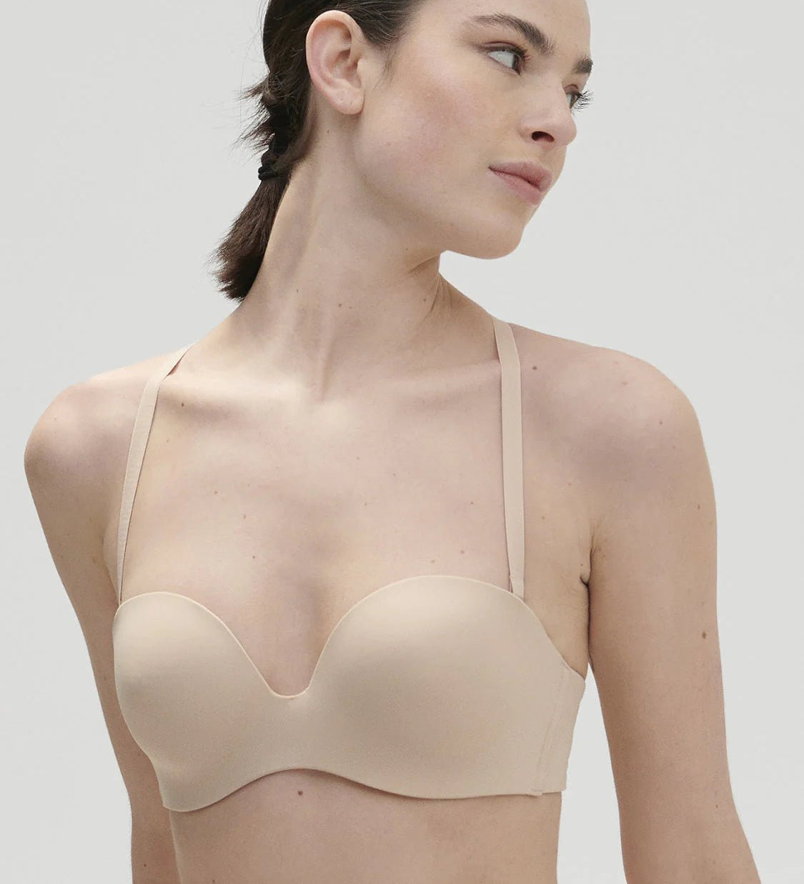 Model wearing Essentiel Multi Strapless Bra Peau Rose, front close-up showing bandeau and moulded cup design.