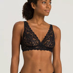 Woman wearing a black lace bralette against a plain background