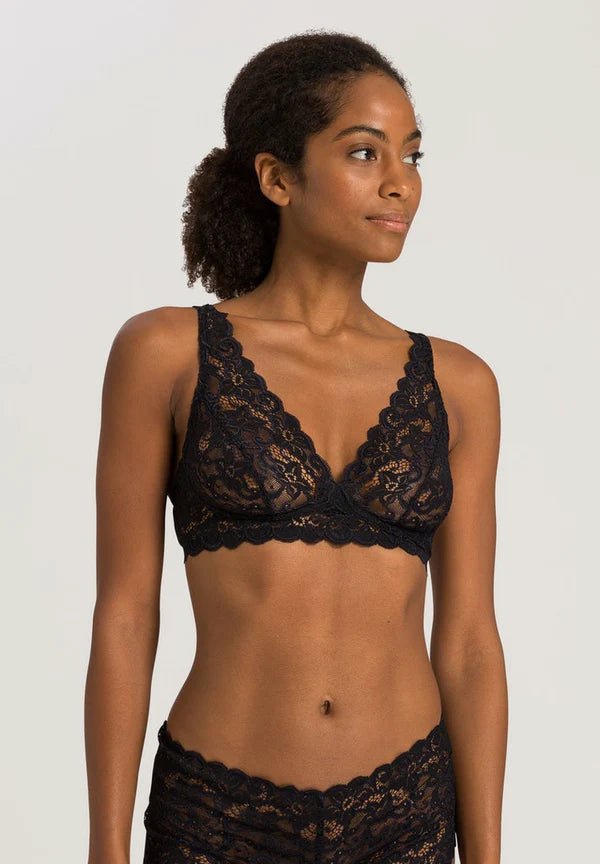 Woman wearing a black lace bralette against a plain background