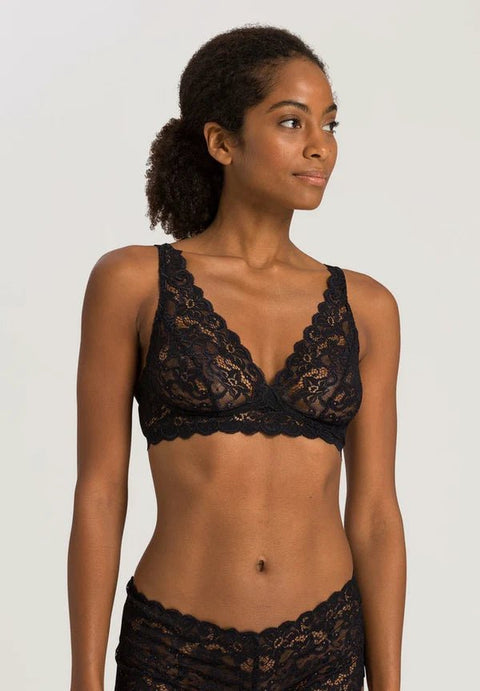 Woman wearing a black lace bralette against a plain background