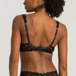 Woman wearing a black lace bra and panties set against a plain background