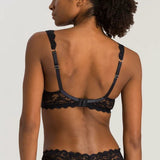 Woman wearing a black lace bra and panties set against a plain background
