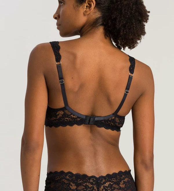 Woman wearing a black lace bra and panties set against a plain background