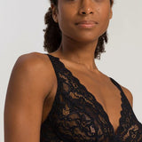 Woman wearing a black lace bralette against a plain background