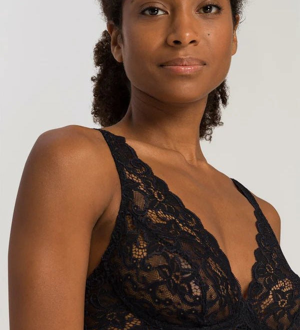 Woman wearing a black lace bralette against a plain background