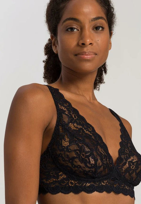 Woman wearing a black lace bralette against a plain background