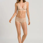 Woman wearing a beige lace lingerie set on a plain background
