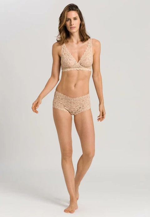 Woman wearing a beige lace lingerie set on a plain background