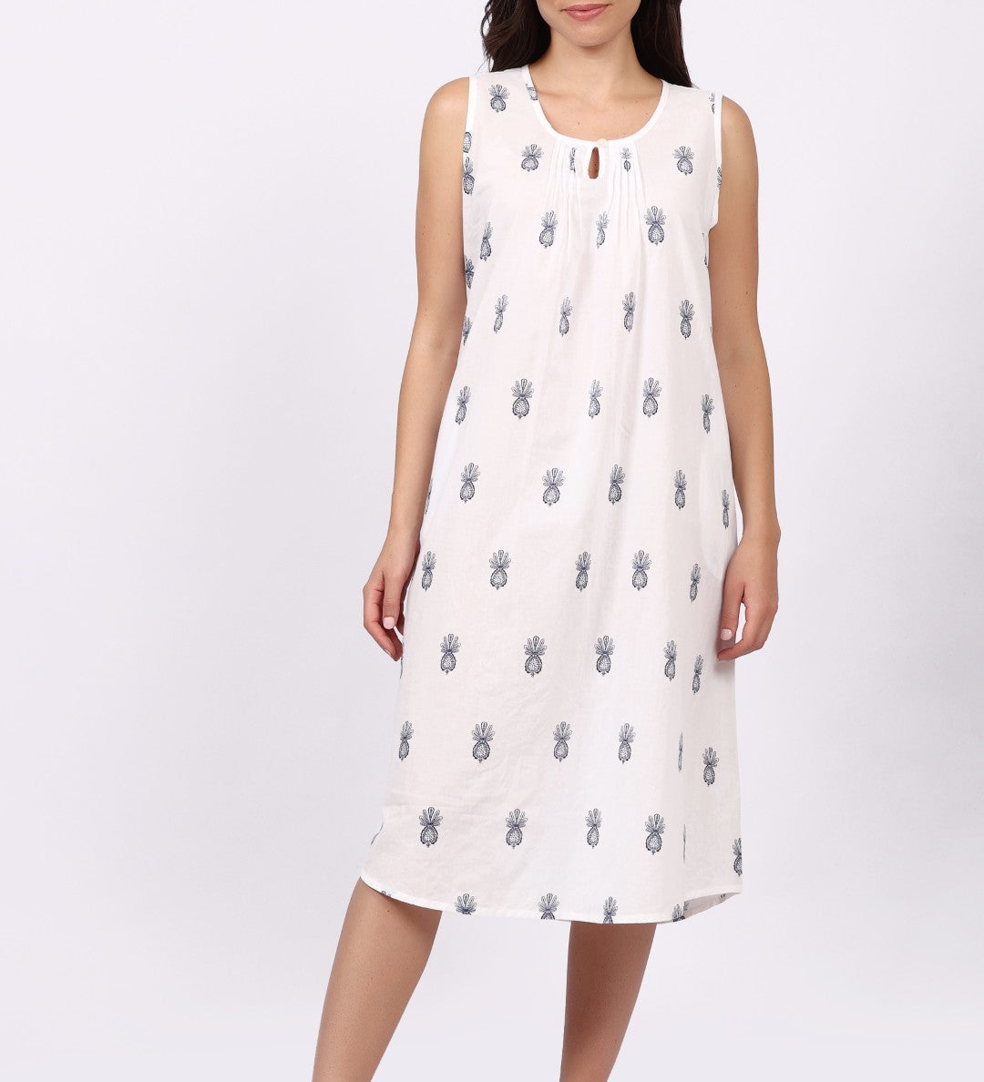 Woman wearing a white sleeveless cotton nightdress with navy patterns on a white background