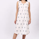 Woman wearing a white sleeveless cotton nightdress with navy patterns on a white background
