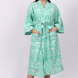 Woman wearing a green floral cotton robe on a white background
