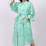 Woman wearing a green floral cotton patterned robe on a white background