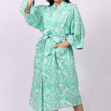 Woman wearing a green floral cotton patterned robe on a white background