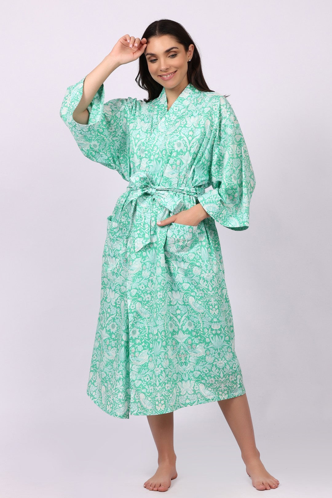 Woman wearing a green floral cotton patterned robe on a white background