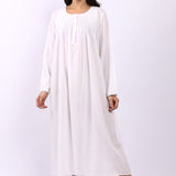 Woman wearing Lotus Sara long sleeve white cotton nightdress with pintuck bodice and rounded neckline.