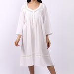 Woman wearing Lotus Susie white cotton nightdress with 3/4 sleeves, lace trim and pintuck bodice.