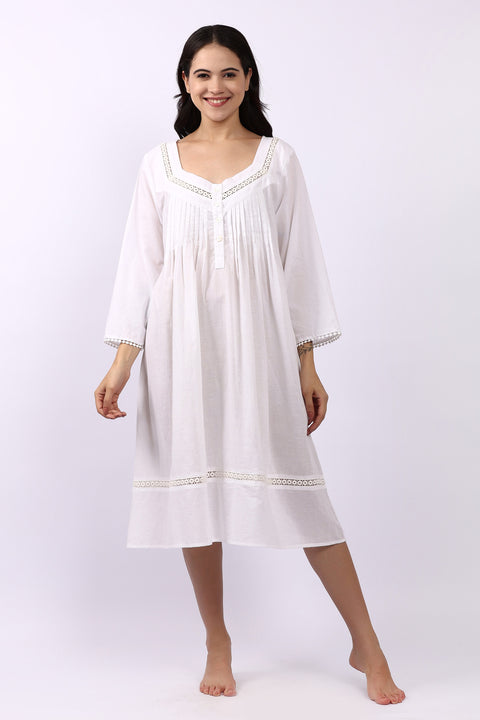 Woman wearing Lotus Susie white cotton nightdress with 3/4 sleeves, lace trim and pintuck bodice.