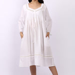 Woman wearing Lotus Susie white cotton nightdress with 3/4 sleeves, lace trim and pintuck bodice.