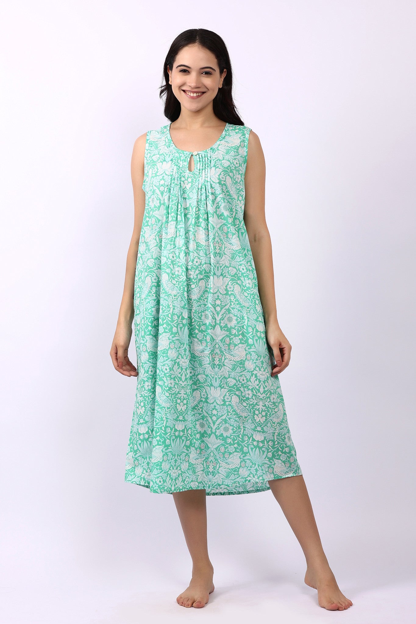 Woman wearing sleeveless cotton nightdress in spearmint green with Strawberry Thief print, keyhole neckline, and relaxed fit.