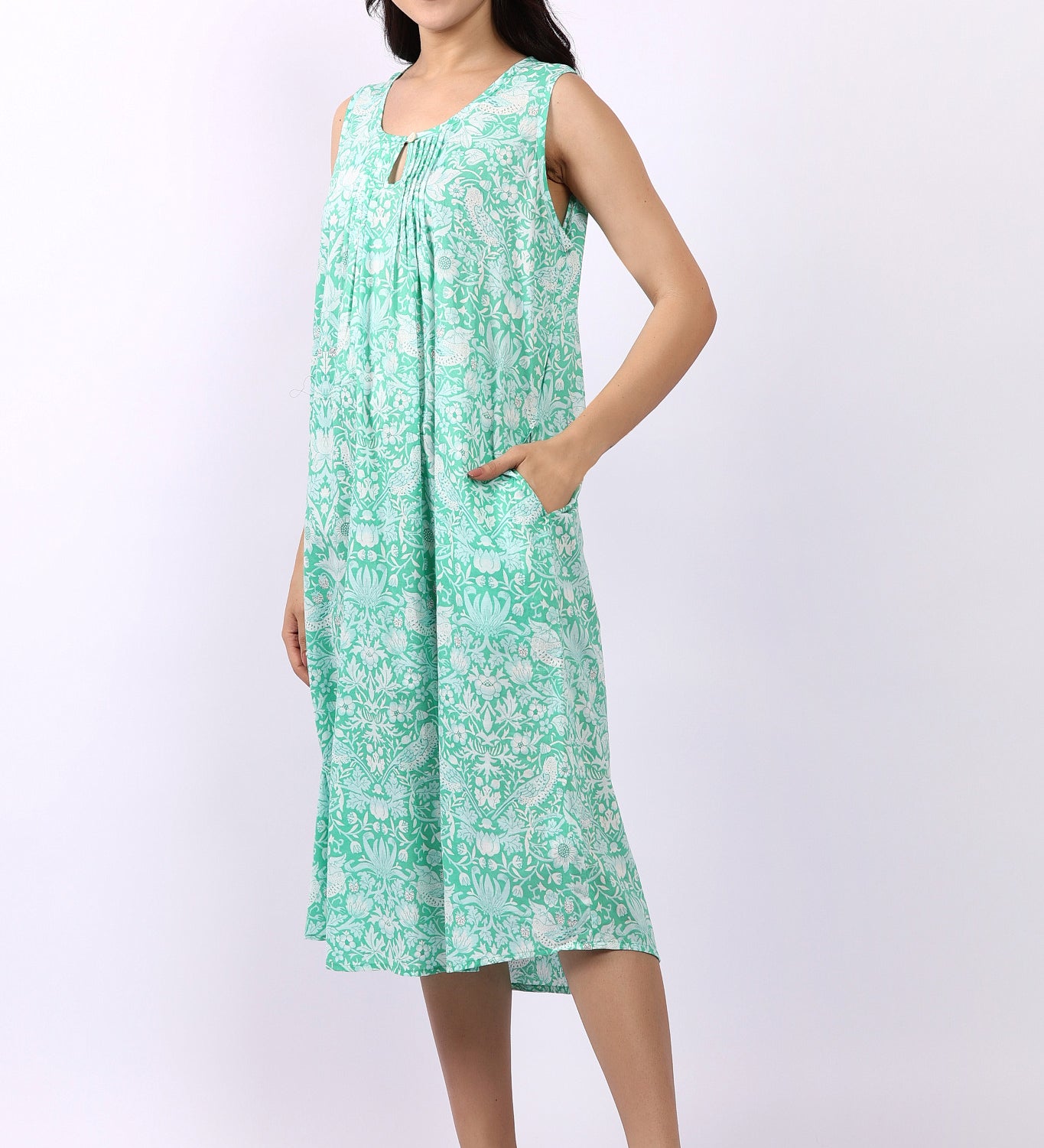 Woman wearing sleeveless cotton nightdress in spearmint green with Strawberry Thief print, keyhole neckline, and relaxed fit.