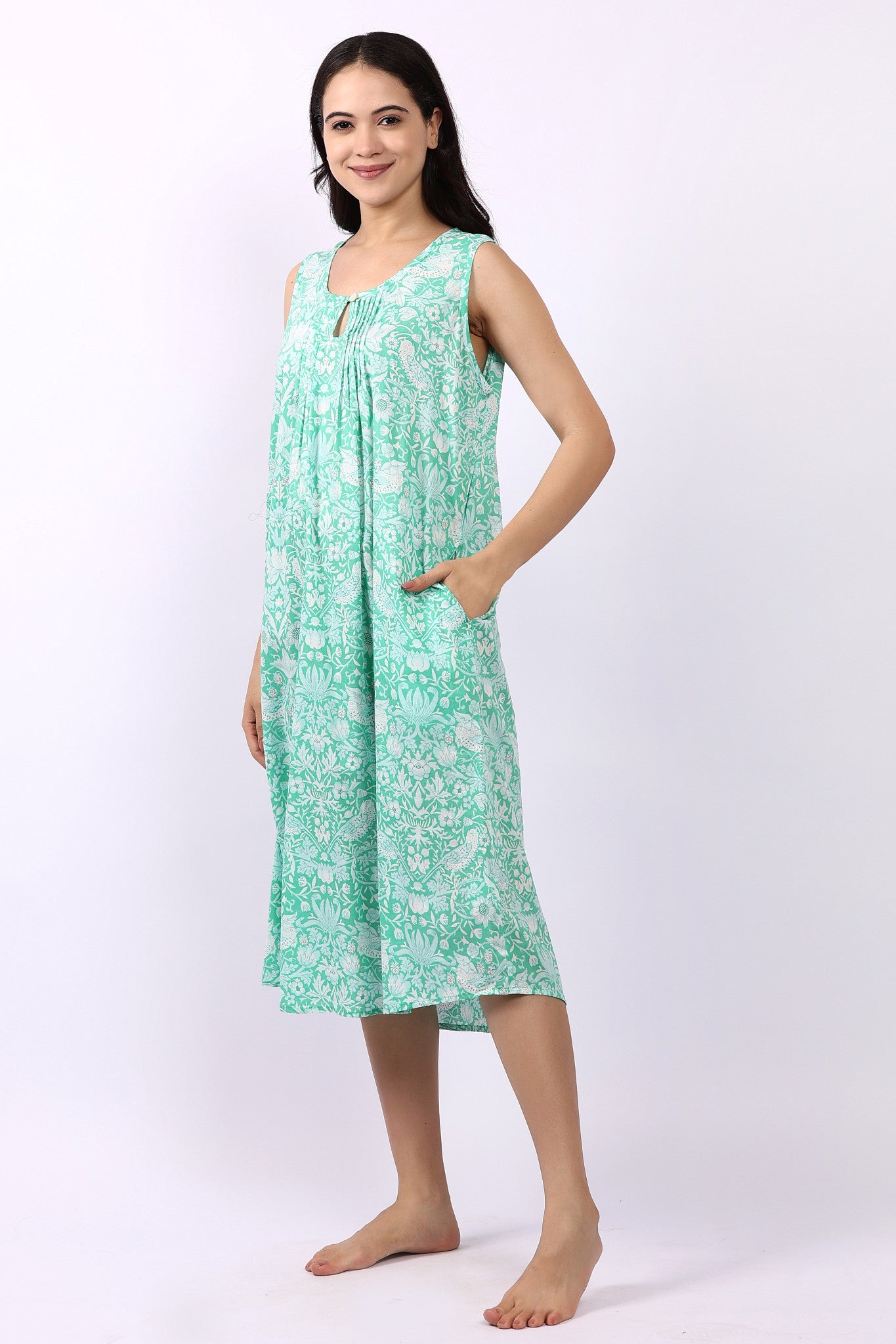 Woman wearing sleeveless cotton nightdress in spearmint green with Strawberry Thief print, keyhole neckline, and relaxed fit.