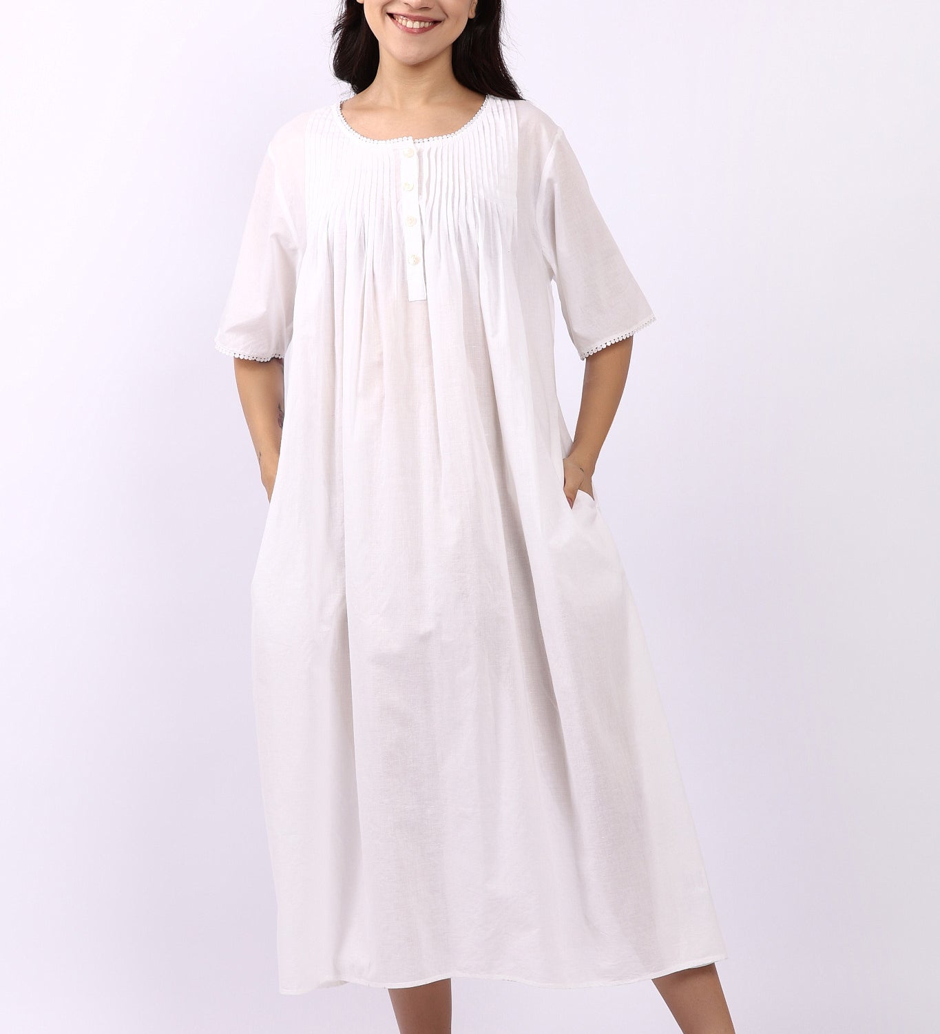 Woman wearing Lotus Sara short sleeve cotton pintuck nightdress in white with side pockets.