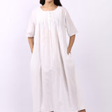Woman wearing Lotus Sara short sleeve cotton pintuck nightdress in white with side pockets.