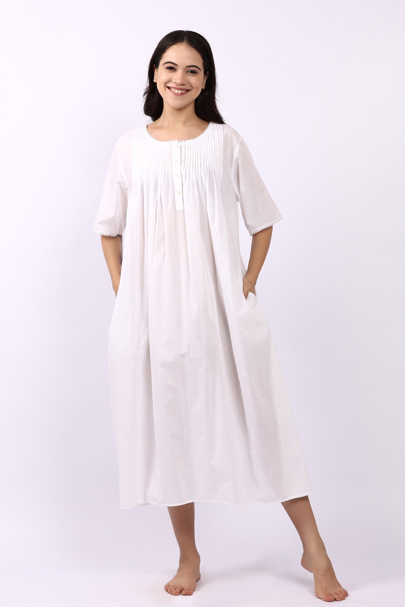 Woman wearing Lotus Sara short sleeve cotton pintuck nightdress in white with side pockets.