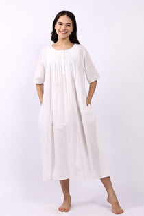 Woman wearing Lotus Sara short sleeve cotton pintuck nightdress in white with side pockets.