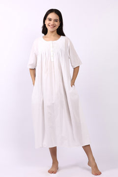 Woman wearing Lotus Sara short sleeve cotton pintuck nightdress in white with side pockets.