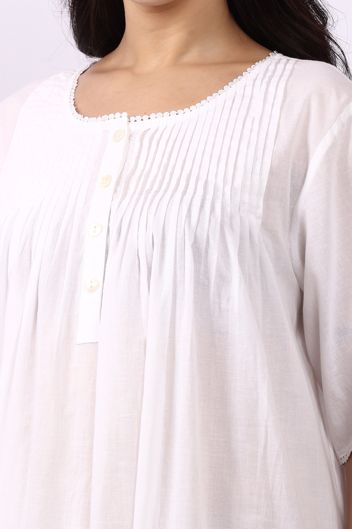 Close-up of pintuck bodice and rounded neckline on Lotus Sara white cotton nightdress.