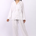 Woman wearing Lotus Jacqui revere long pyjama set in white self-stripe cotton, shirt and pants.