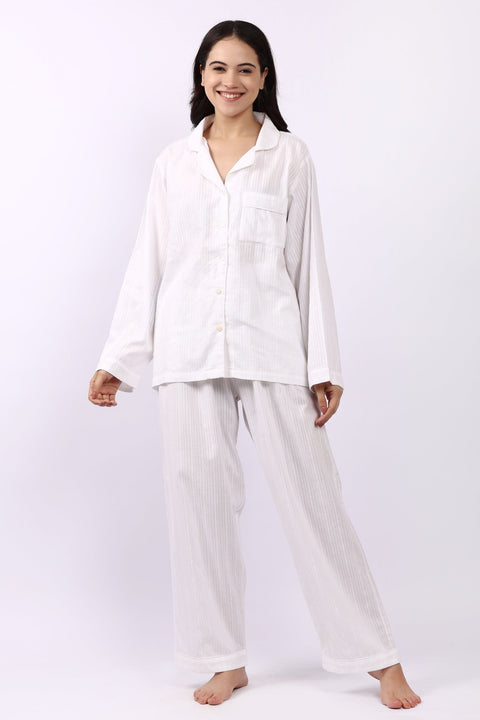 Woman wearing Lotus Jacqui revere long pyjama set in white self-stripe cotton, shirt and pants.