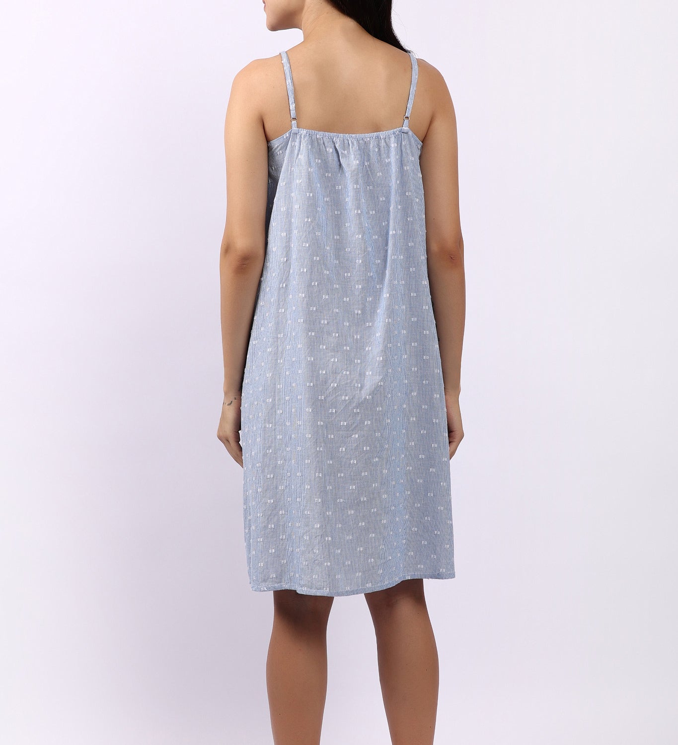 Woman wearing a light blue nightgown with thin straps on a white background