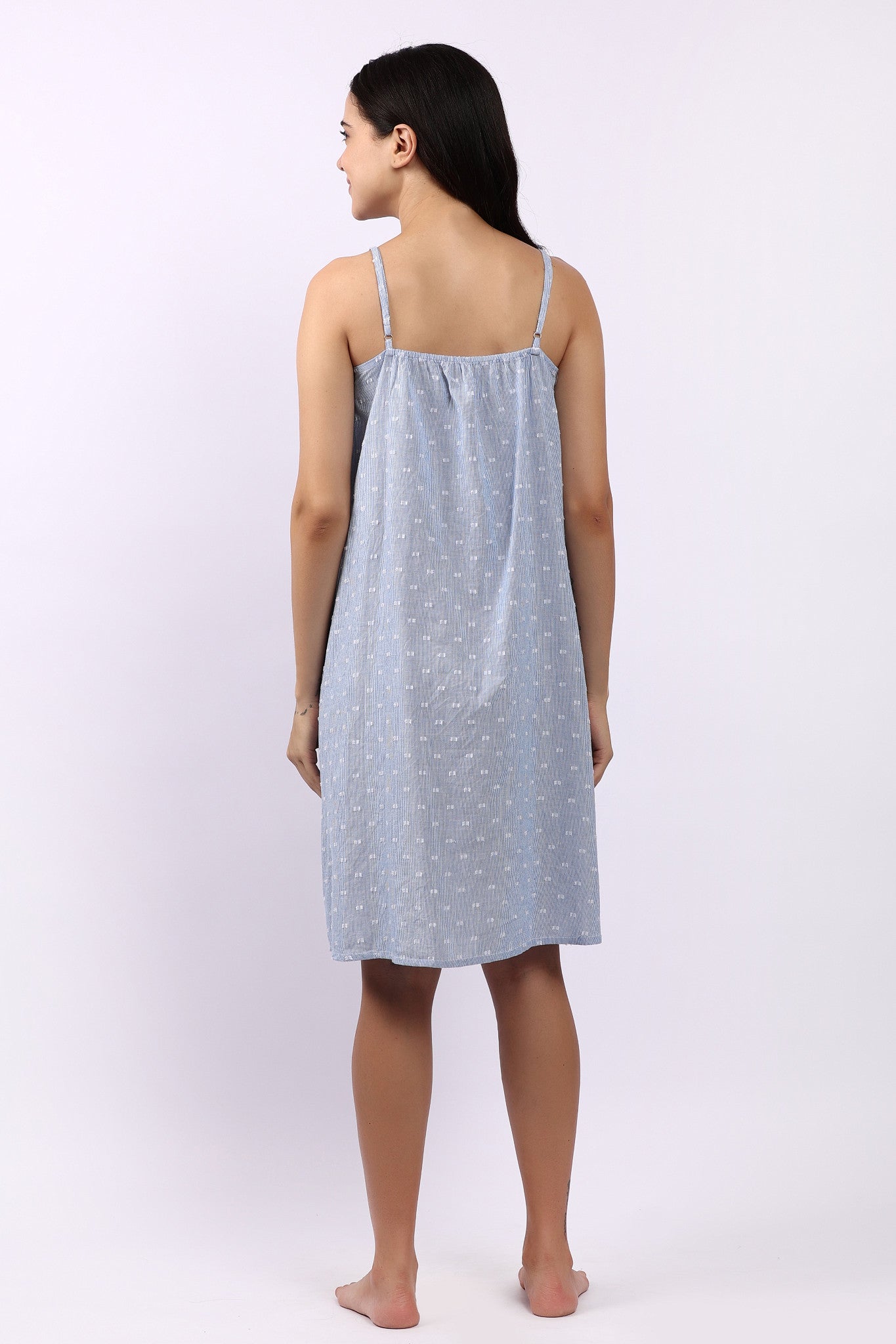 Woman wearing a light blue nightgown with thin straps on a white background