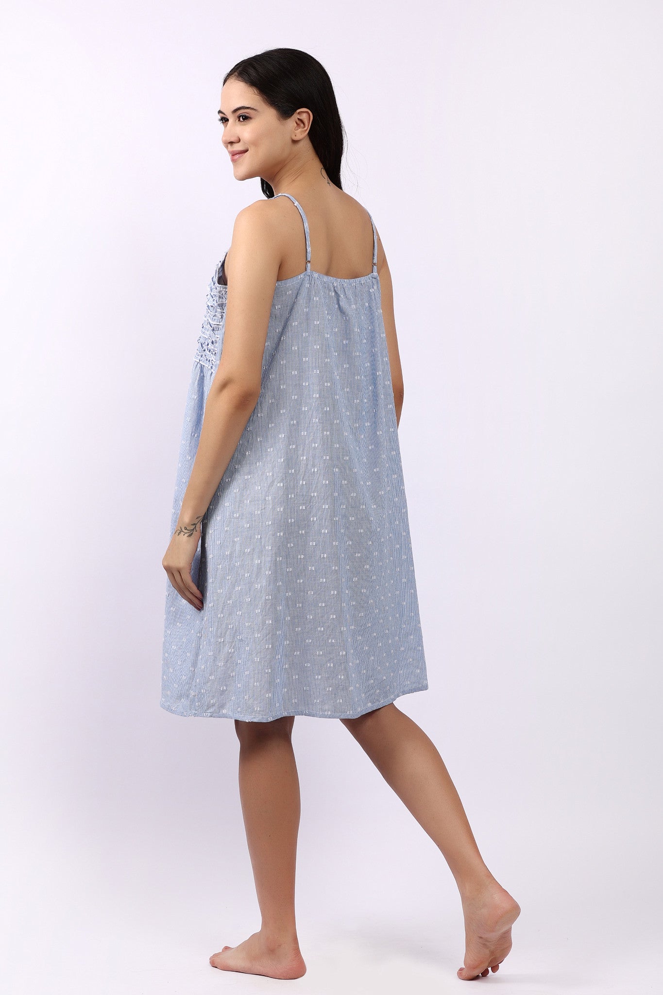 Woman wearing a light blue dress with thin straps on a white background