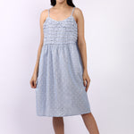 Woman wearing a light blue dress with thin straps on a white background