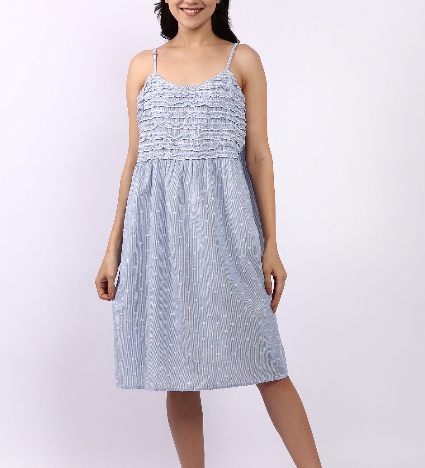 Woman wearing a light blue dress with thin straps on a white background