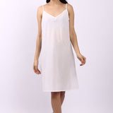 Woman wearing Lotus bias cut white cotton slip with slim straps, ideal as petticoat or summer nightie.