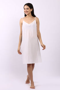 Woman wearing Lotus bias cut white cotton slip with slim straps, ideal as petticoat or summer nightie.