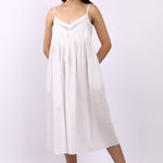 Woman wearing Lotus Susie spaghetti strap white cotton nightdress with lace-trim neckline and pintuck bodice.