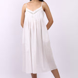 Woman wearing Lotus Susie spaghetti strap white cotton nightdress with lace-trim neckline and pintuck bodice.