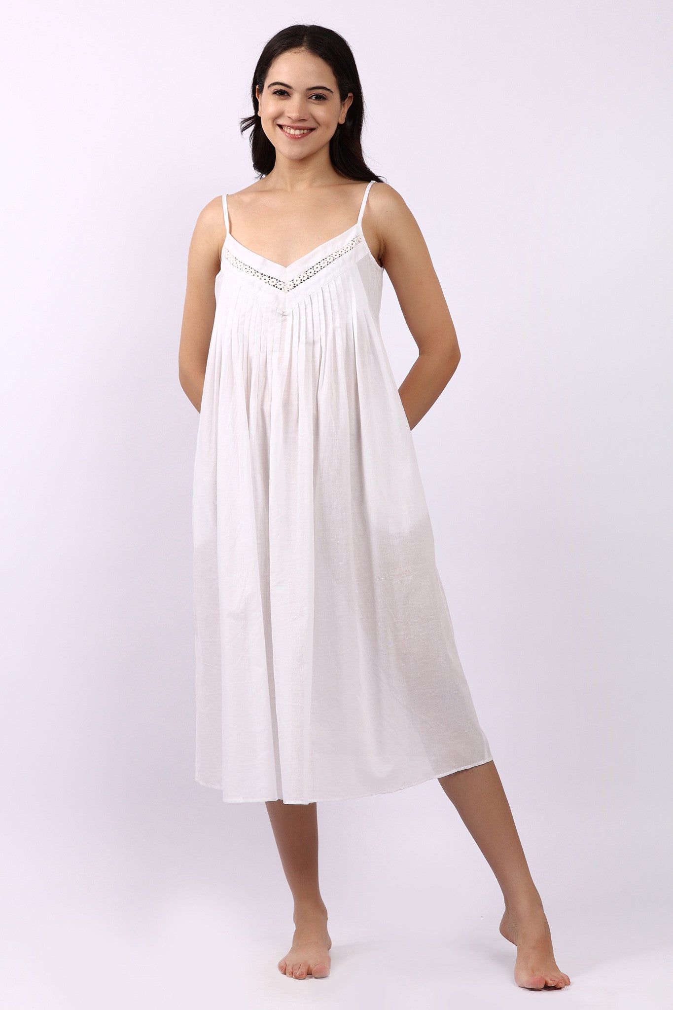 Woman wearing Lotus Susie spaghetti strap white cotton nightdress with lace-trim neckline and pintuck bodice.
